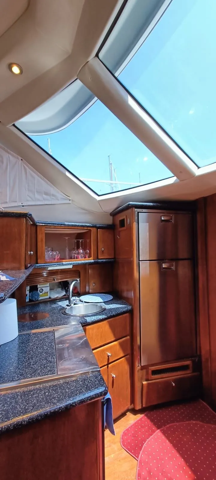 The galley below the salon's sunroof, wood cabinetry and a stainless sink under open sky